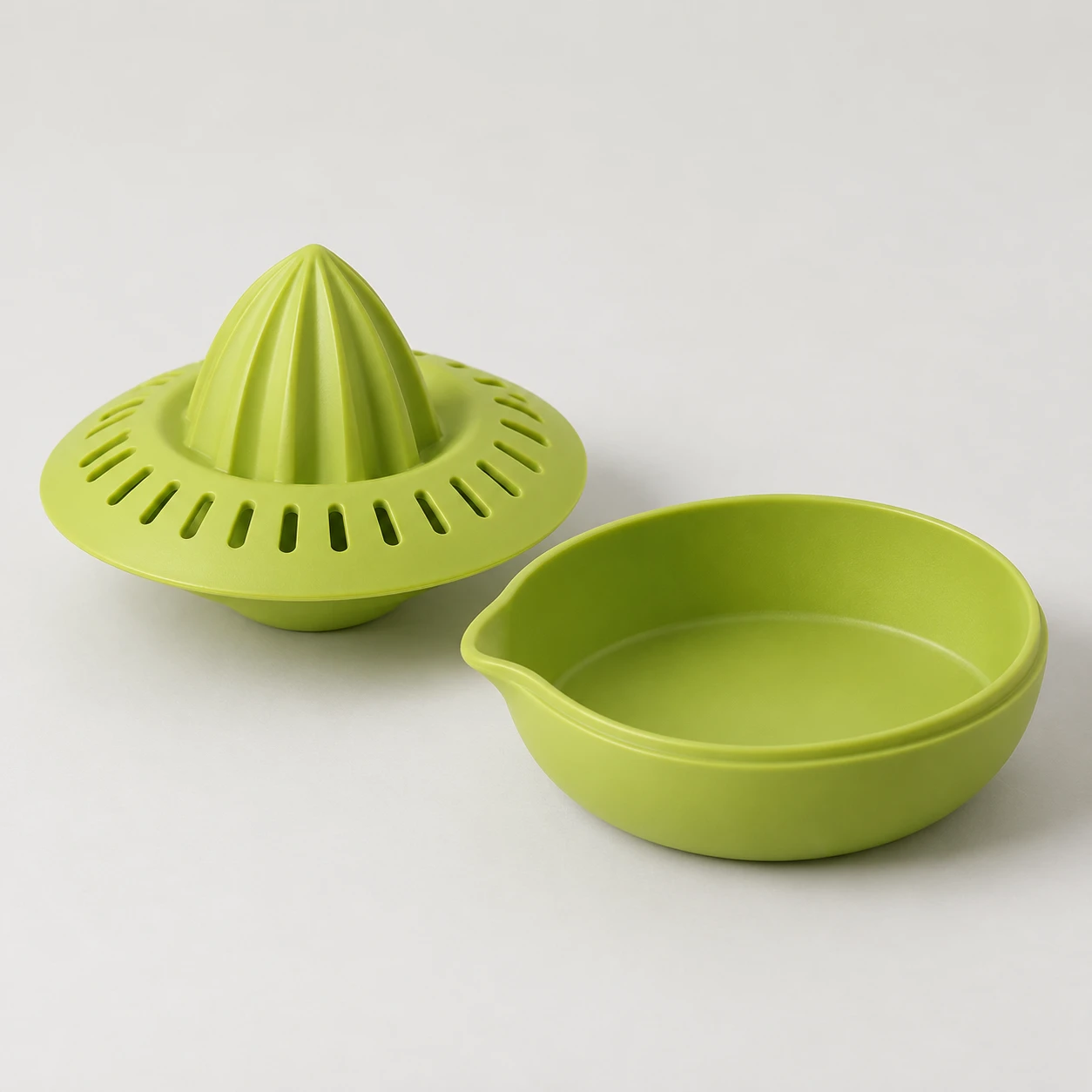 Lime-green saucer-shaped citrus juicer with its matching catch bowl beside it.