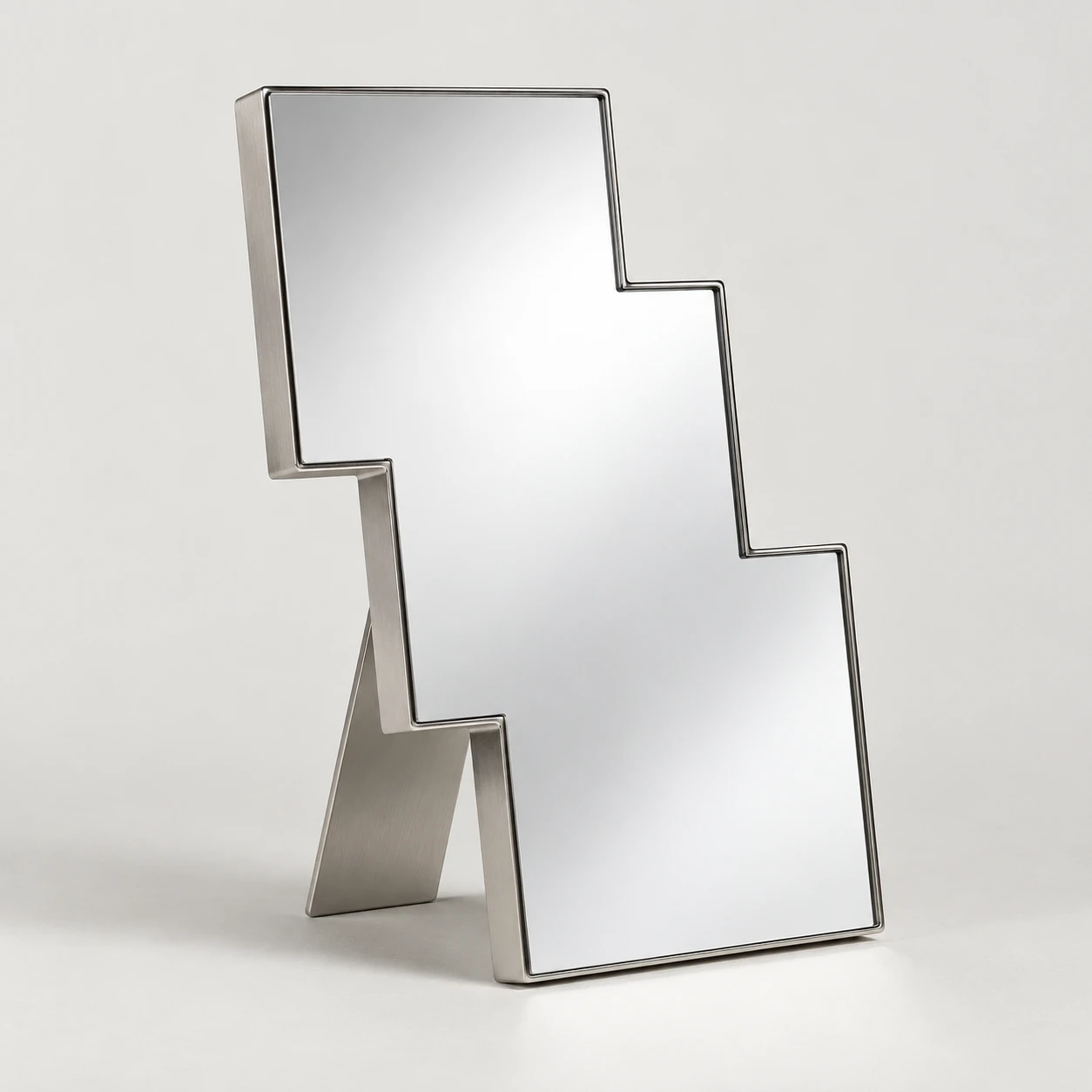 Polished tabletop mirror with a stepped outline and folded metal stand.