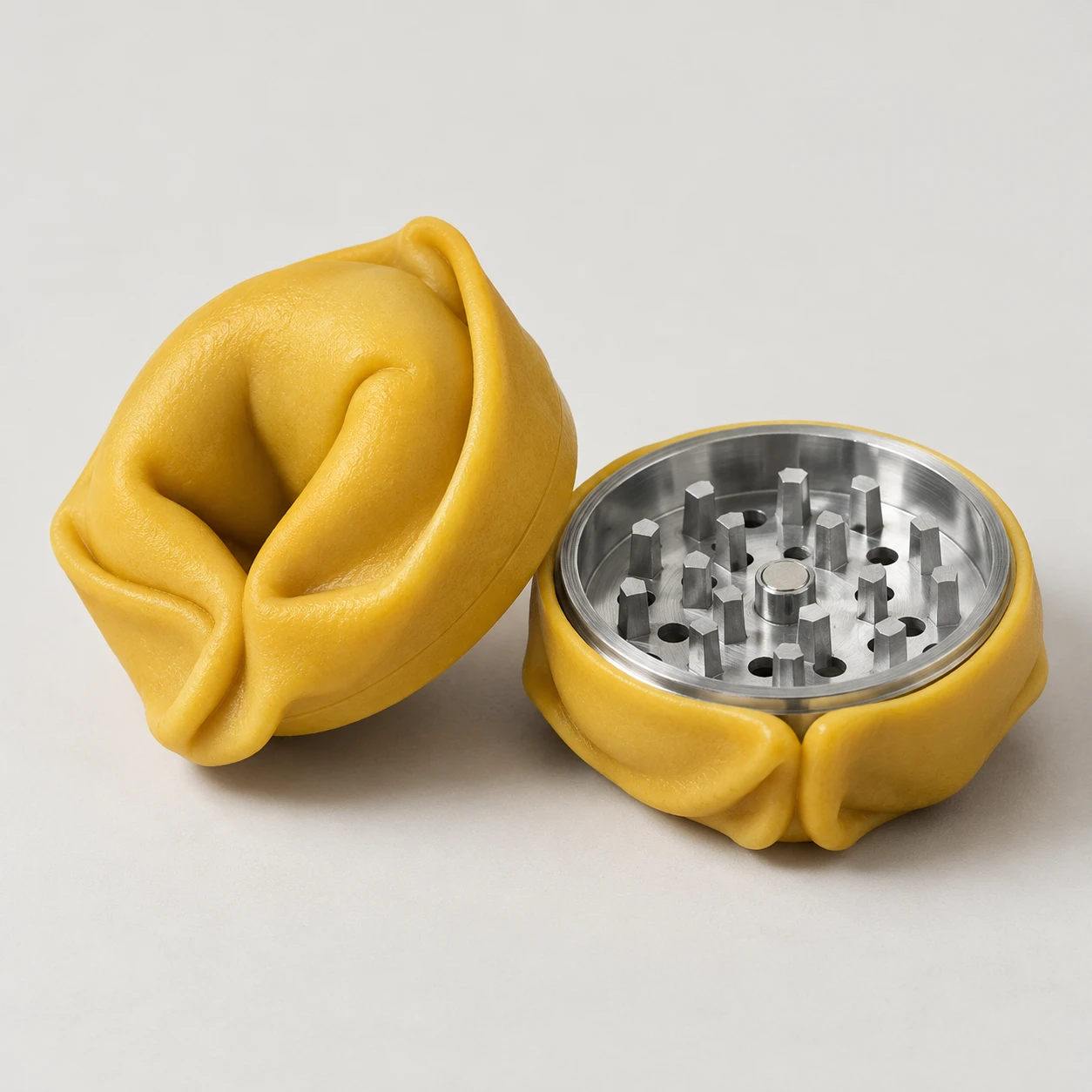 Studio photograph of an open tortellino-shaped grinder with machined aluminum teeth.