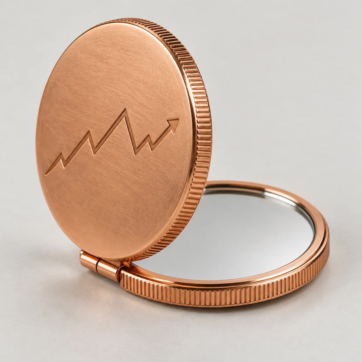 Open copper-colored compact mirror with a ridged edge and engraved zigzag arrow.