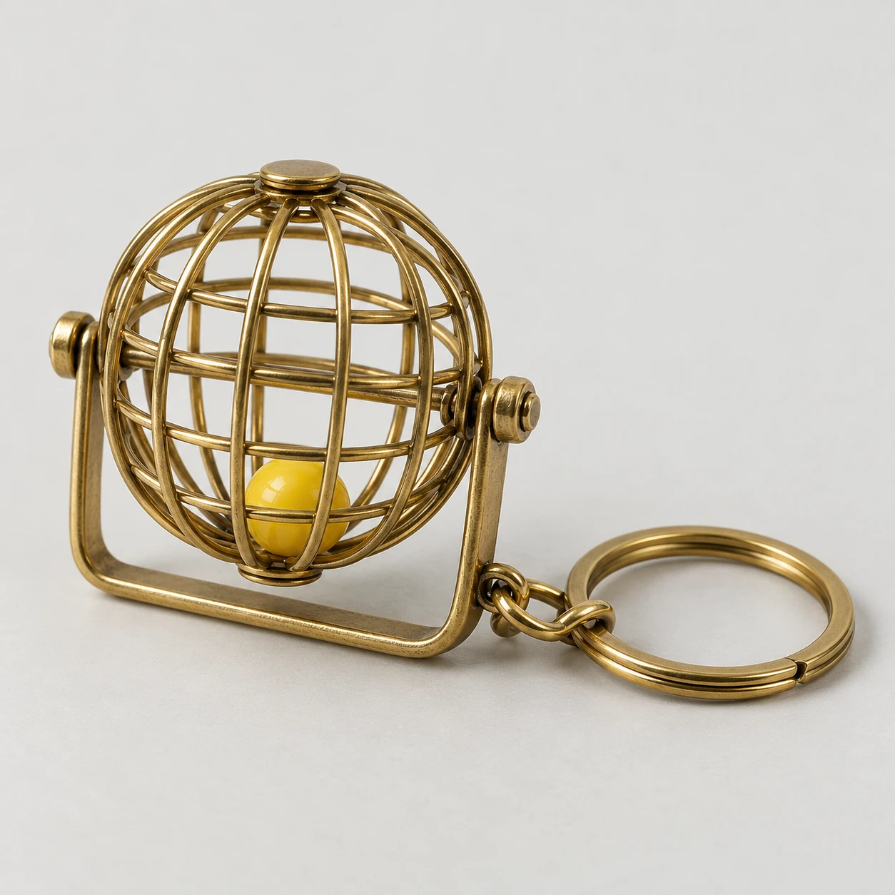 Brass bingo-cage keyring with a yellow bead inside.