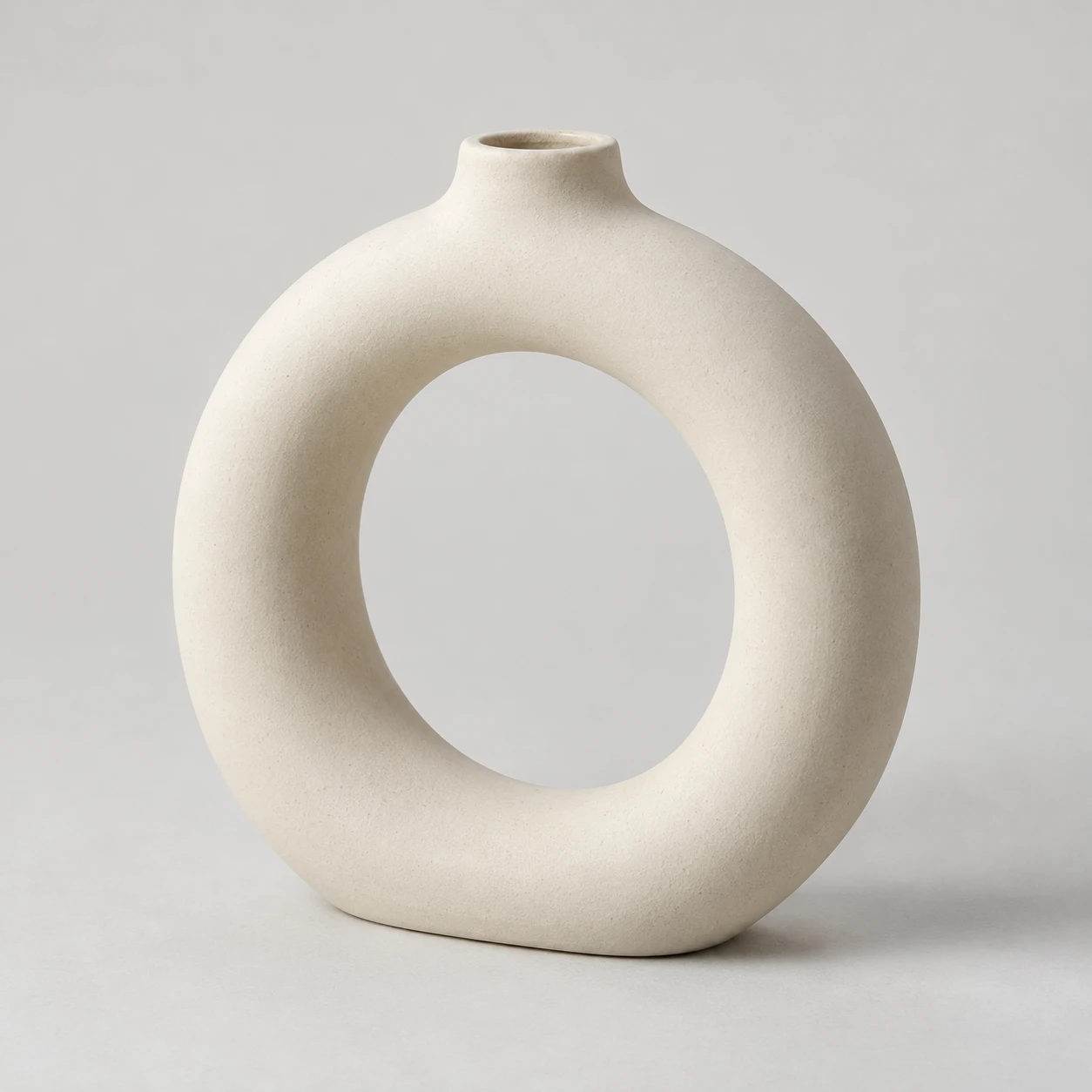 Matte ivory ring-shaped vase with a large open center and small top opening.